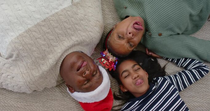 Senior couple, Youth girl celebrating, starting tongues out, laughing in Santa hat, headband on rug