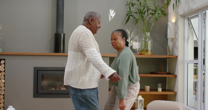 Senior couple dancing near fireplace, man starting touch near waist leading into soft sway