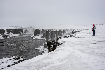 Hiker watching Selfoss waterfall in the snowy canyon in Iceland © Andrea Tabaro