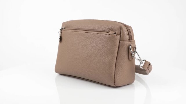 Professional 4k product video of a light brown leather women purse rotating 360 degrees on a white background, highlighting elegant design and textured leather.