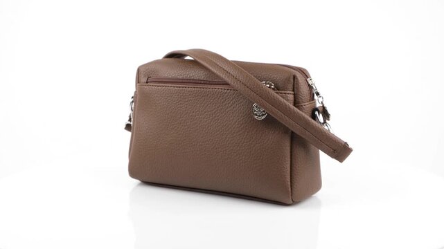 Clean 360 degree rotating view of a brown leather women shoulder bag on an isolated white studio background, high quality commercial product video shot in 4k.