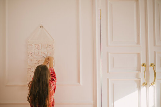 Cute 7-years old girl looking for a present in her Christmas advent calendar.