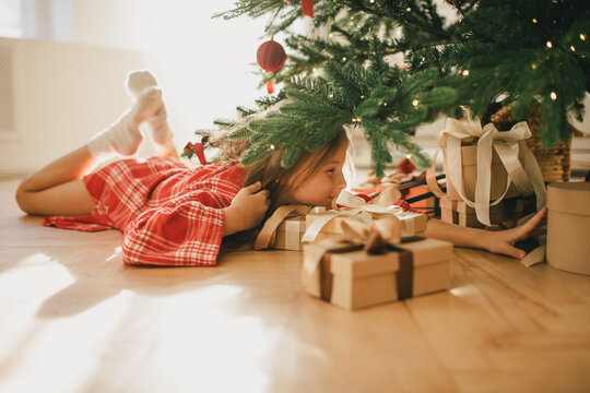 Cute 7-years old girl looking for a present under Christmas tree.