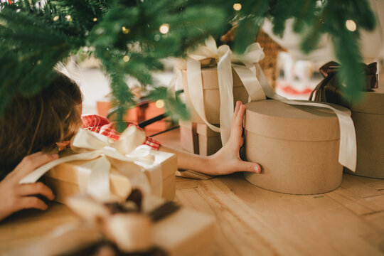 Cute 7-years old girl looking for a present under Christmas tree.