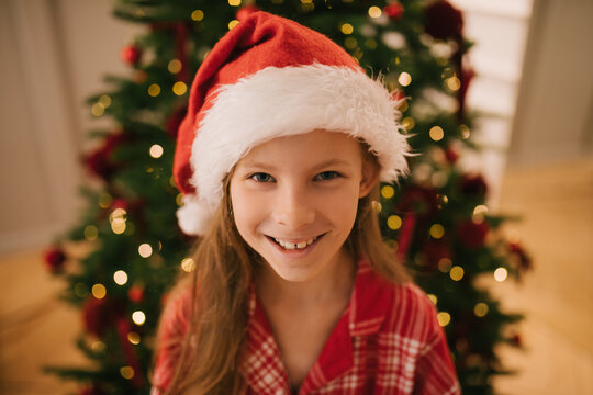 Cute 7-years old girl portrait near decorated Christmas tree.
