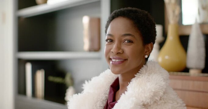 African woman facing camera at home smiling laughing softening wearing fur coat and pearls