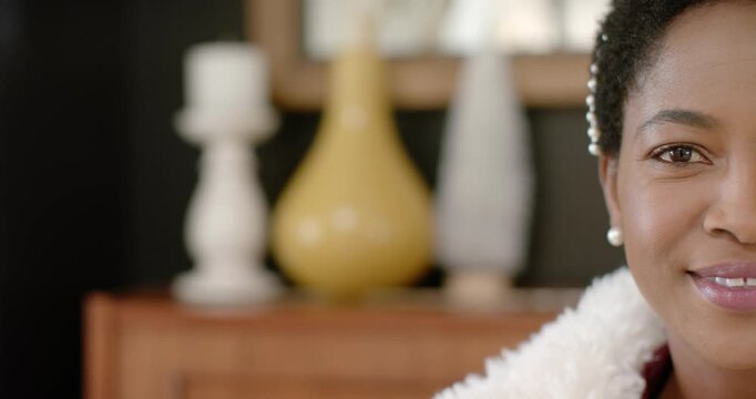 Camera shifting, woman wearing pearls softening face and smiling at camera in home, copy space