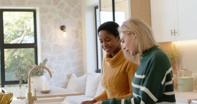 Diverse women friends offering herb, chopping and sprinkling at counter, finishing roast to serve