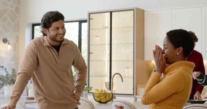 Couple greeting at kitchen island, woman clapping then arranging table with turkey for dinner