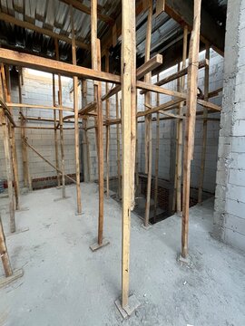 Wooden Scaffolding and Props Supporting Ceiling Construction Inside Unfinished Building with Concrete Block Walls