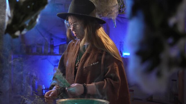realistic witch brewing a potion. She makes a bouquet of dried herbs and recites a spell. Everyday life and traditional witchcraft. Magic and a mystical atmosphere.