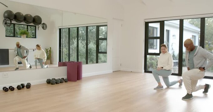 African American trainer and client after cue doing lunges in mirror studio for health, copy space