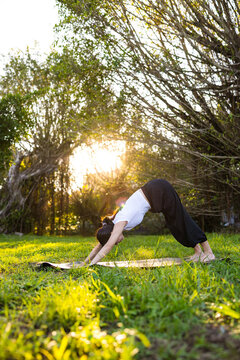 Woman doing downward dog yoga pose in park