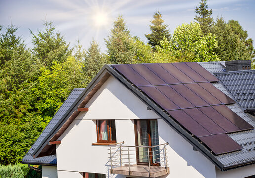 Solar electric panels on the house roof. Blue sky background and rays of the sun. Photovoltaic panel, new technology. Concept of eco, clean ecological electric energy, zero emission.