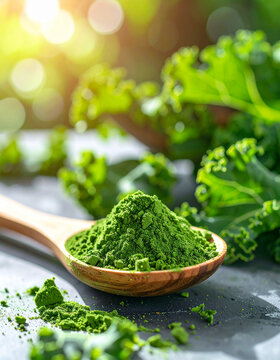 Fine green kale powder in wooden spoon with fresh curly kale scattered around it, natural textures, organic superfood concept. Close-up.