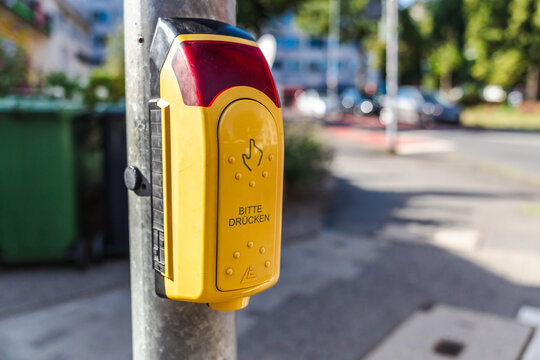 Yellow pedestrian crossing button on street pole in Germany