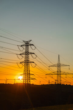 Electricity Pylons Silhouetted Against Orange Sunset in Germany