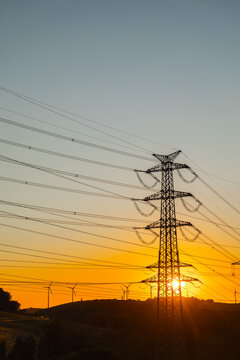 Power Transmission Tower and Wind Turbines at Sunset