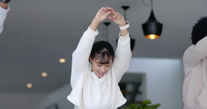Diverse group following Asian woman at home raising arms folding onto green mat doing yoga stretch
