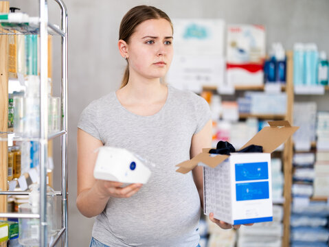 Pregnant woman chooses tonometer to measure blood pressure at pharmacy