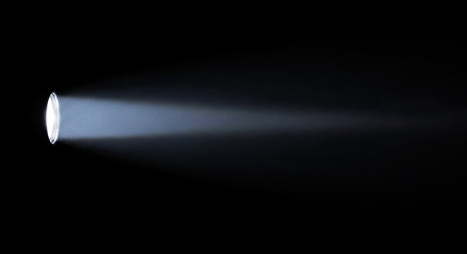 A bright flashlight beam illuminates a dark space. The focused light creates a cone-shaped shadow on a black background.