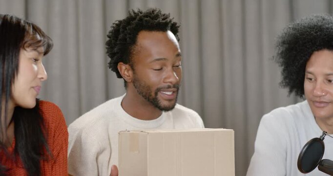 African American trio with center presenter holding box, hosting product discussion with laptop