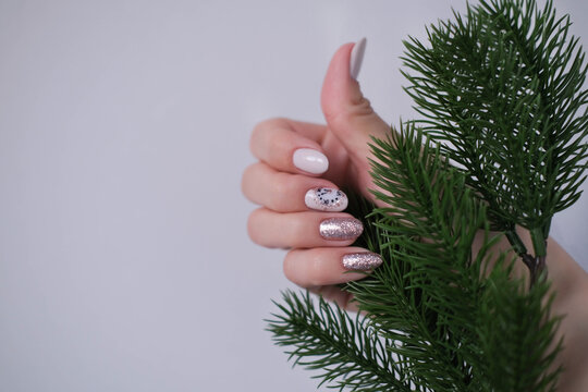 A beautiful Christmas manicure. A woman's hand holds a spruce branch, showcasing a beautiful nail design.