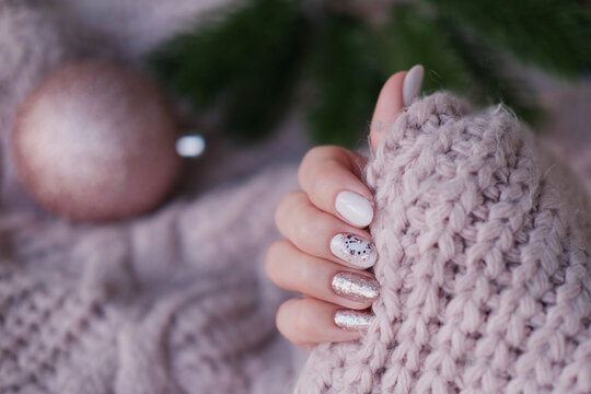 A beautiful Christmas manicure. A woman's hand in a knitted sweater, featuring a beautiful nail design.