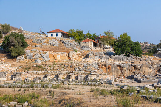 Patara, ancient city ruins located near Kalkan, Turkey. Weathered ancient ruins reveal crumbling colonnade fragments, carved capitals, and scattered stone blocks on a rocky hillside