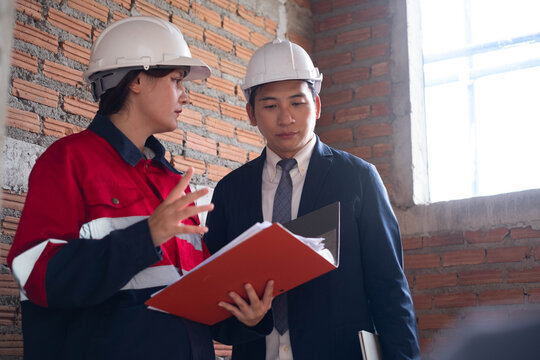 Construction professionals discuss building plans at an unfinished site, showing teamwork, engineering, architecture, project management, collaboration, communication, inspection, and planning.