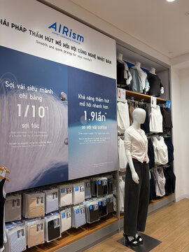 A retail Uniqlo store with clothing display featuring a mannequin dressed in casual wear. The backdrop highlights the AIRism product line with promotional text and numbers. 