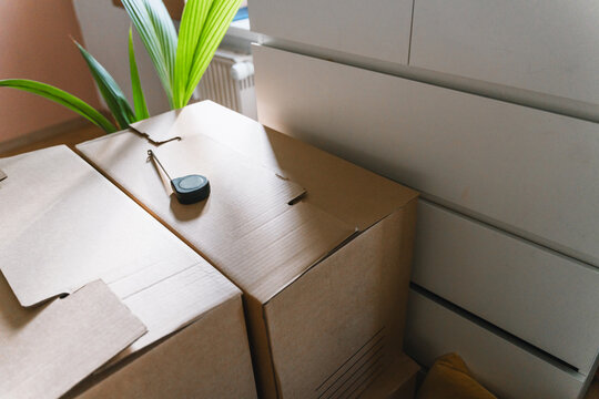 Retracted measuring tape rest on top of closed cardboard moving boxes in a bright room. Home renovation planning and successful relocation real estate concept.