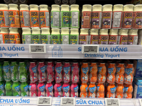 A colorful display of drinking yogurt in cans arranged on shelves. The cans feature various flavors and vibrant colors, making the product visually appealing. 