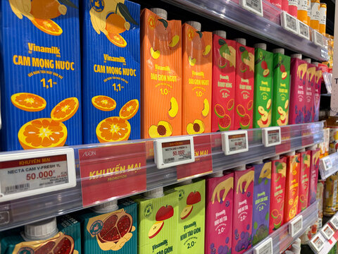 A vibrant display of colorful juice cartons on a supermarket shelf. The cartons feature various fruit illustrations and bright packaging. The scene reflects a lively grocery shopping experience.