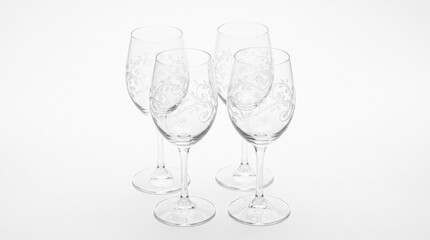 Fototapeta premium Four clear wine glasses with etched floral patterns arranged on a white background