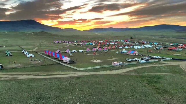 Aerial drone view of a Mongolian camp with basketball play at sunset near a village.