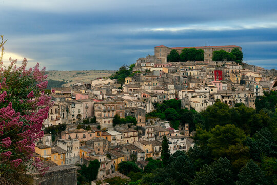 Charming medieval hillside town in Europe with vibrant spring blossoms under cloudy dawn skies