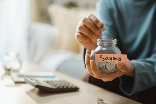 A palm drops a coin as saving and money and savings and goal and planning lead, then saving and money and savings and goal and planning lead a future cushion at a desk in close detail for the future.