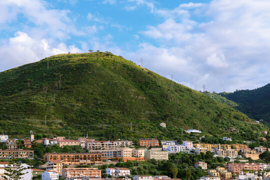 coastal town nestled on lush green terraced hills under a bright cloudy summer sky peaceful tranquil landscape environment space