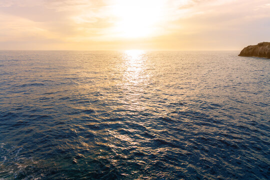 Tranquil ocean horizon view with warm sunlight glistening across the gentle evening waves