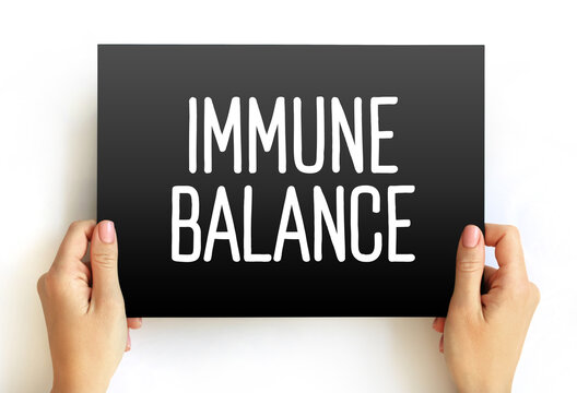 IMMUNE BALANCE text displayed on a hand-held card. Healthcare theme emphasizing the equilibrium of the bodys defense system for optimal health and disease prevention.