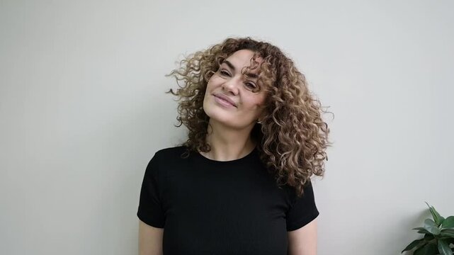 Woman shakes her head, making long defined curls bounce and fly through the air. Dynamic demonstration of curl movement, volume and elasticity after styling.
