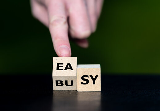 A hand turns letter cubes from BUSY to EASY, symbolizing simpler workflows, reduced workload, greater efficiency and better work-life balance.