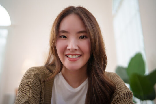 Smiling young woman looking at the camera in a bright home interior, representing happiness, friendly expression, positive lifestyle and relaxed mood.