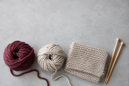 Yarn balls and knitting needles with knitted fabric and copy space