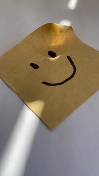 Smiley face sticky note with sunlight on white background