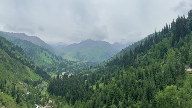 Medeu Mountain Valley Near Almaty Kazakhstan, Lush Tien Shan Forest and Mountain Peaks Covered in Mist Under an Overcast Sky
