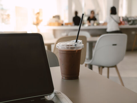 Laptop and Iced Chocolate Drink on Table in Modern Cafe for Remote Work or Study