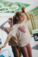 Two young children practicing balance and movement in a kids fitness class. A boy and girl follow...