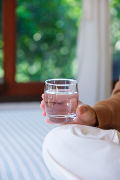 Vertical closeup image of a woman holding a glass of drinking water